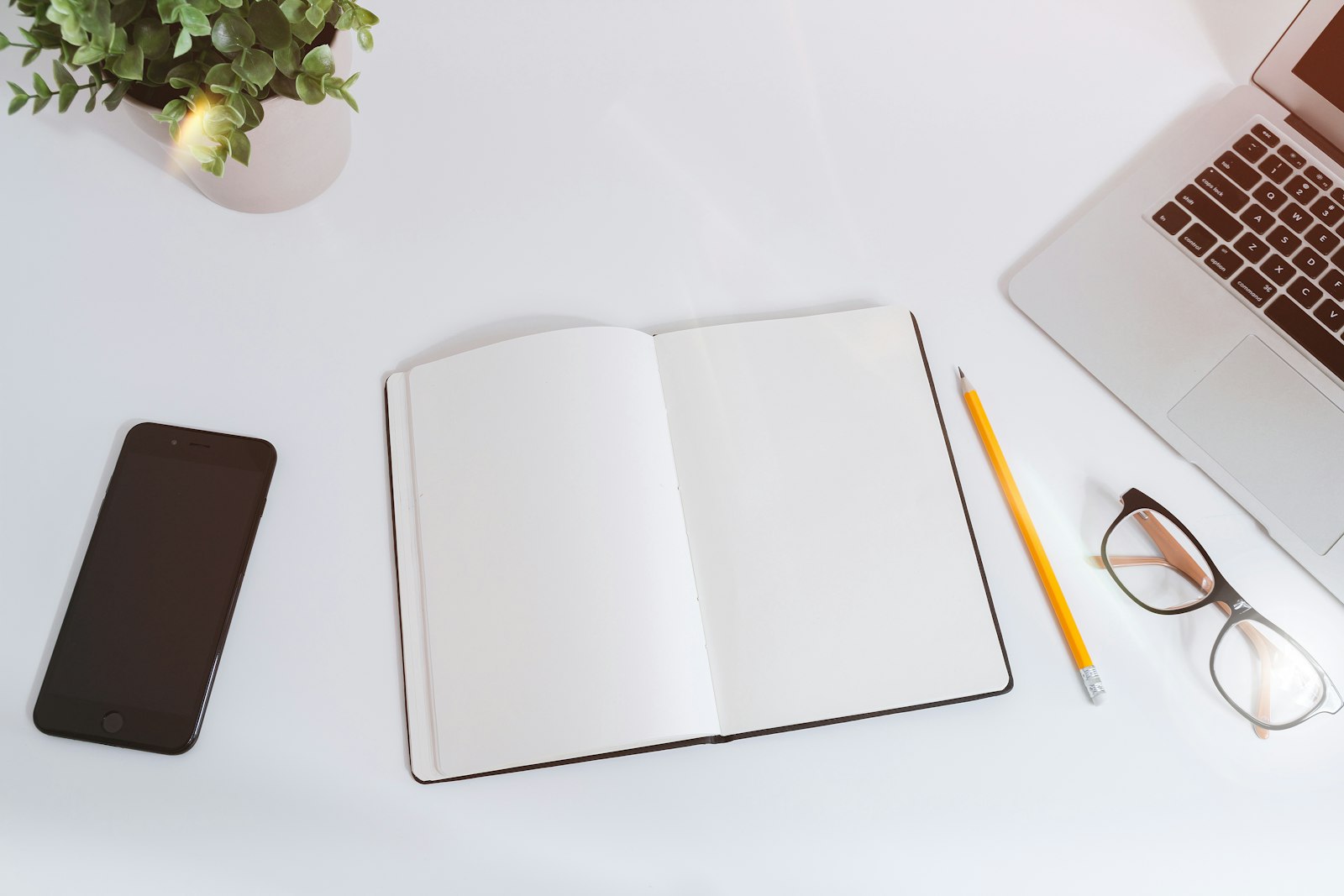 A notebook and laptop on a clean desk, ready for the conversation